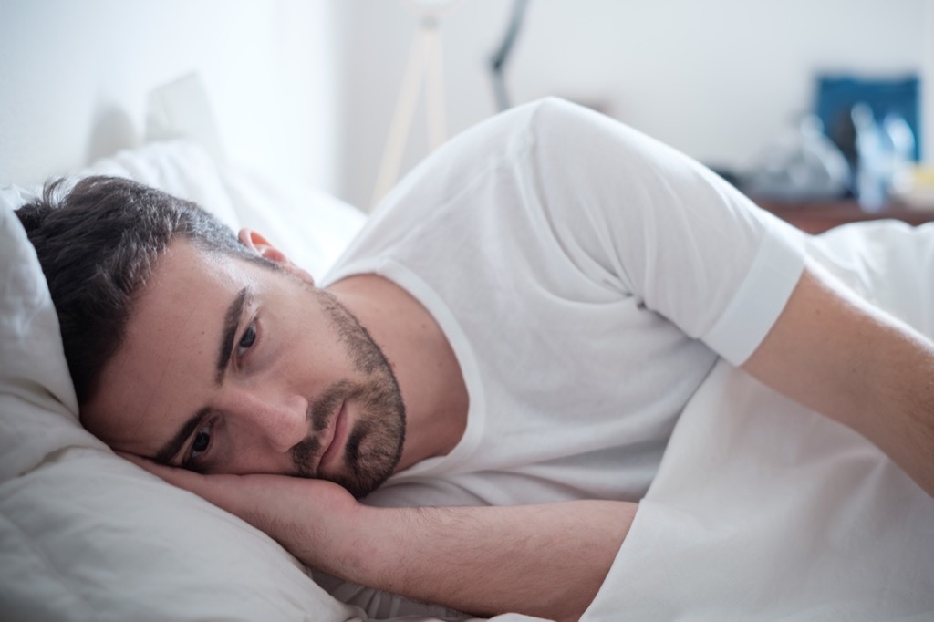 man lying in bed sad