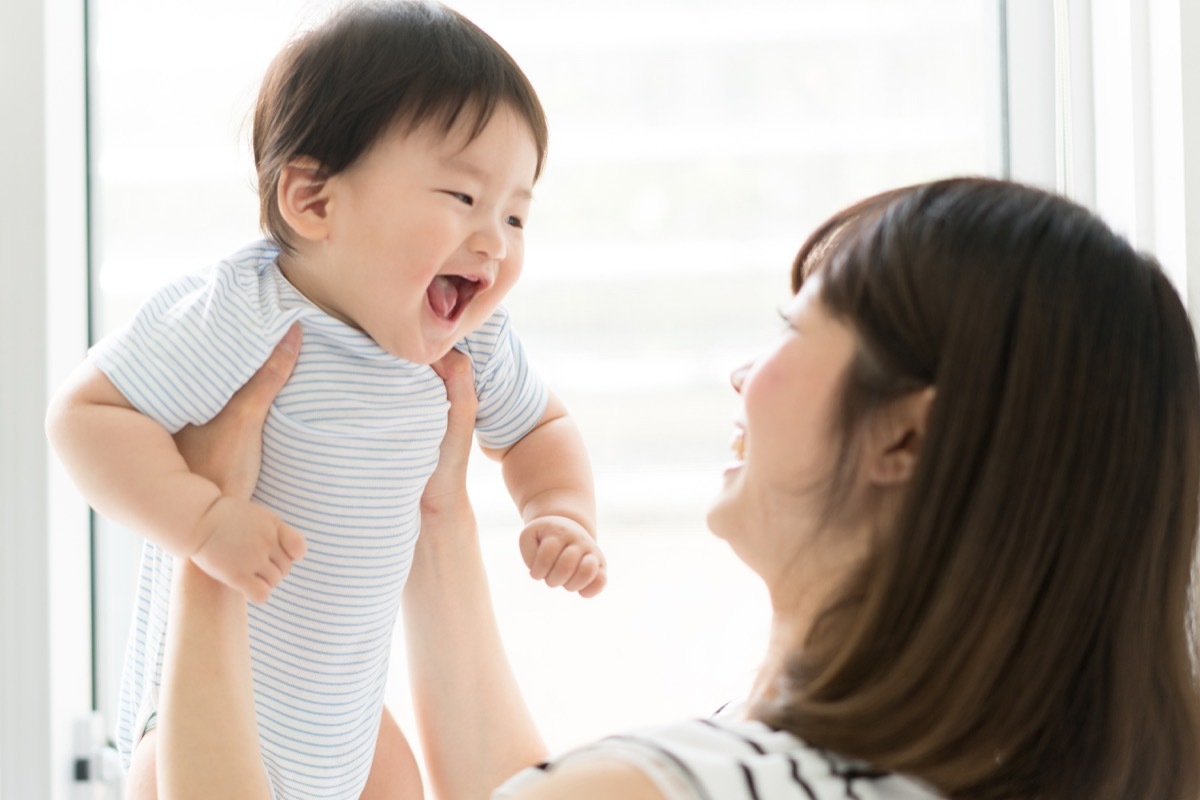 young asian mom holding baby in blue onesie