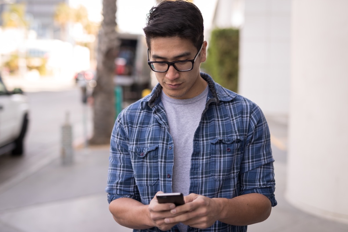 man using cell phone on sidewalk