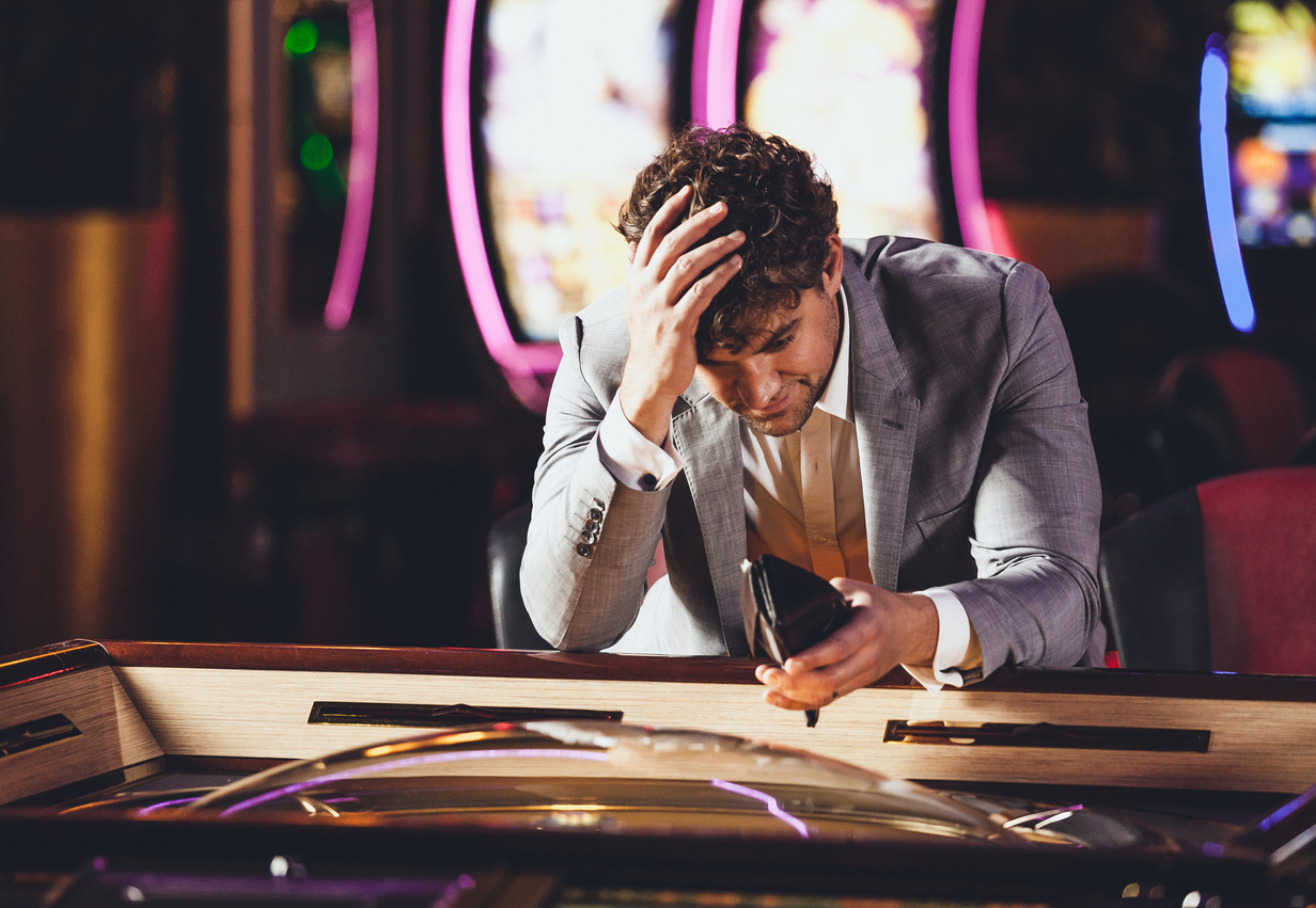 A man looking into his empty wallet at a casino