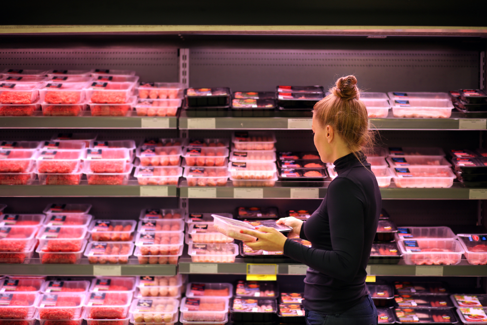 A woman shopping for meat in the grocery store