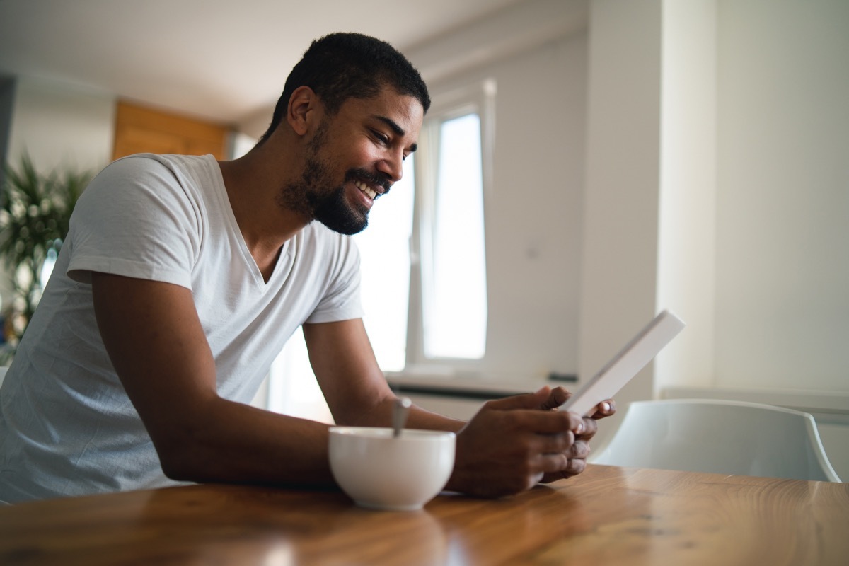 man is browsing social media on tablet while having cereal breakfast.