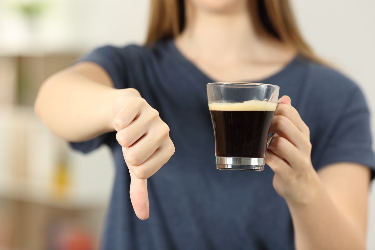 a woman holds a thumbs down and a cup of coffee