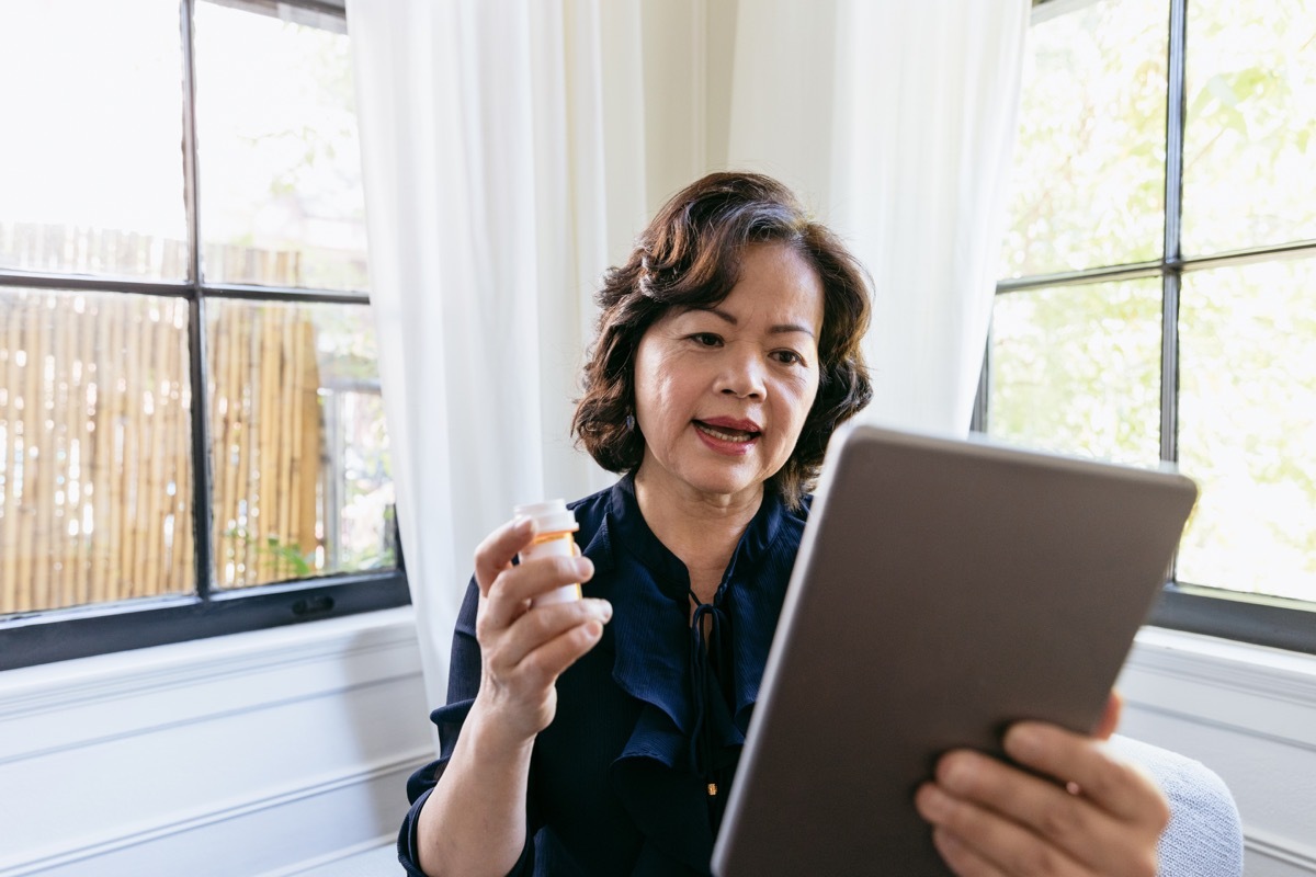 Senior woman discusses her prescription medication with a doctor via video conference. The woman is using a digital tablet.