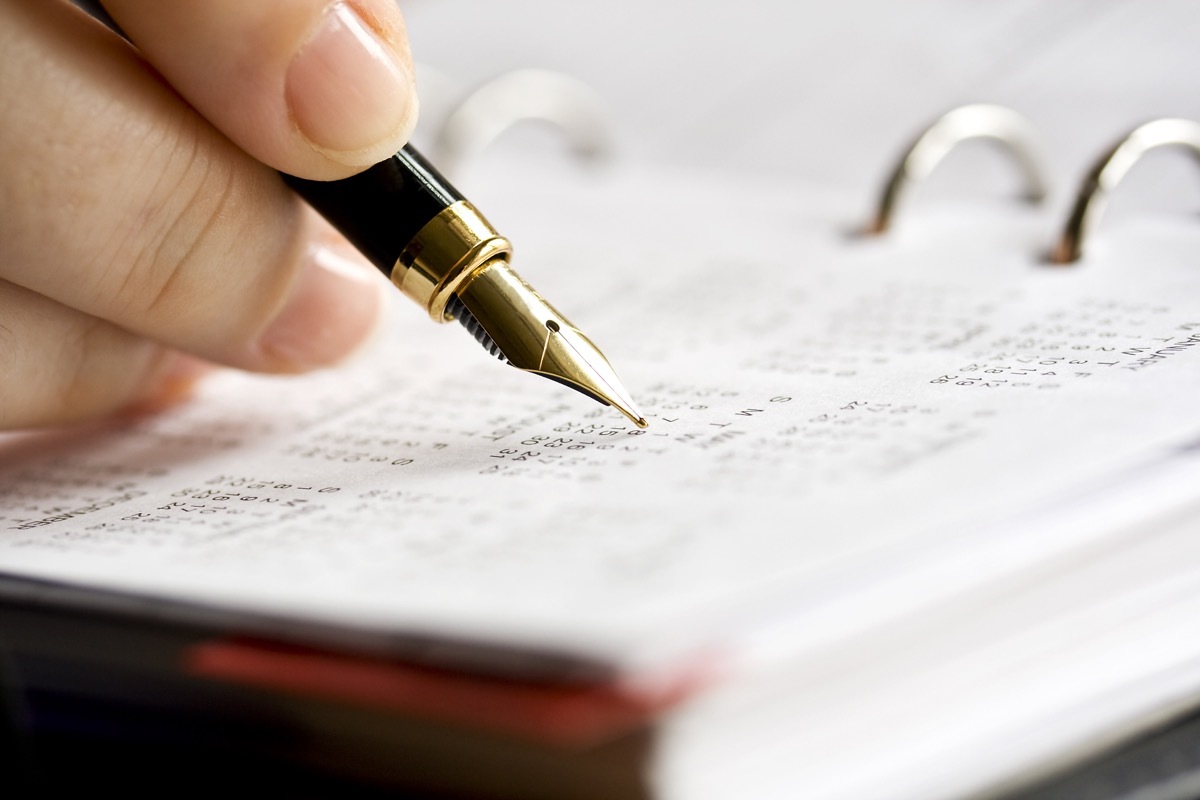 Close-up image of an businesswoman's hand scheduling date in personal organizer