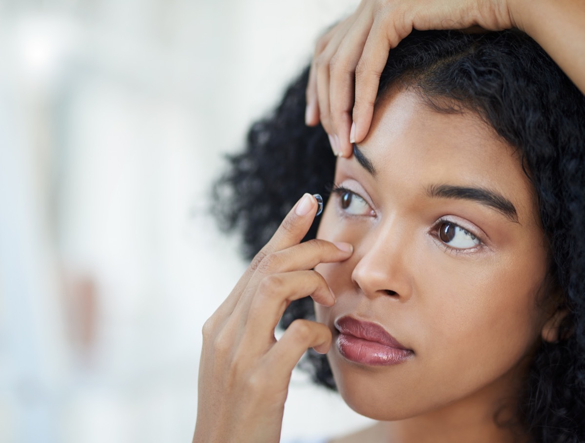 Cropped shot of a beautiful young woman putting in her contact lenses at home