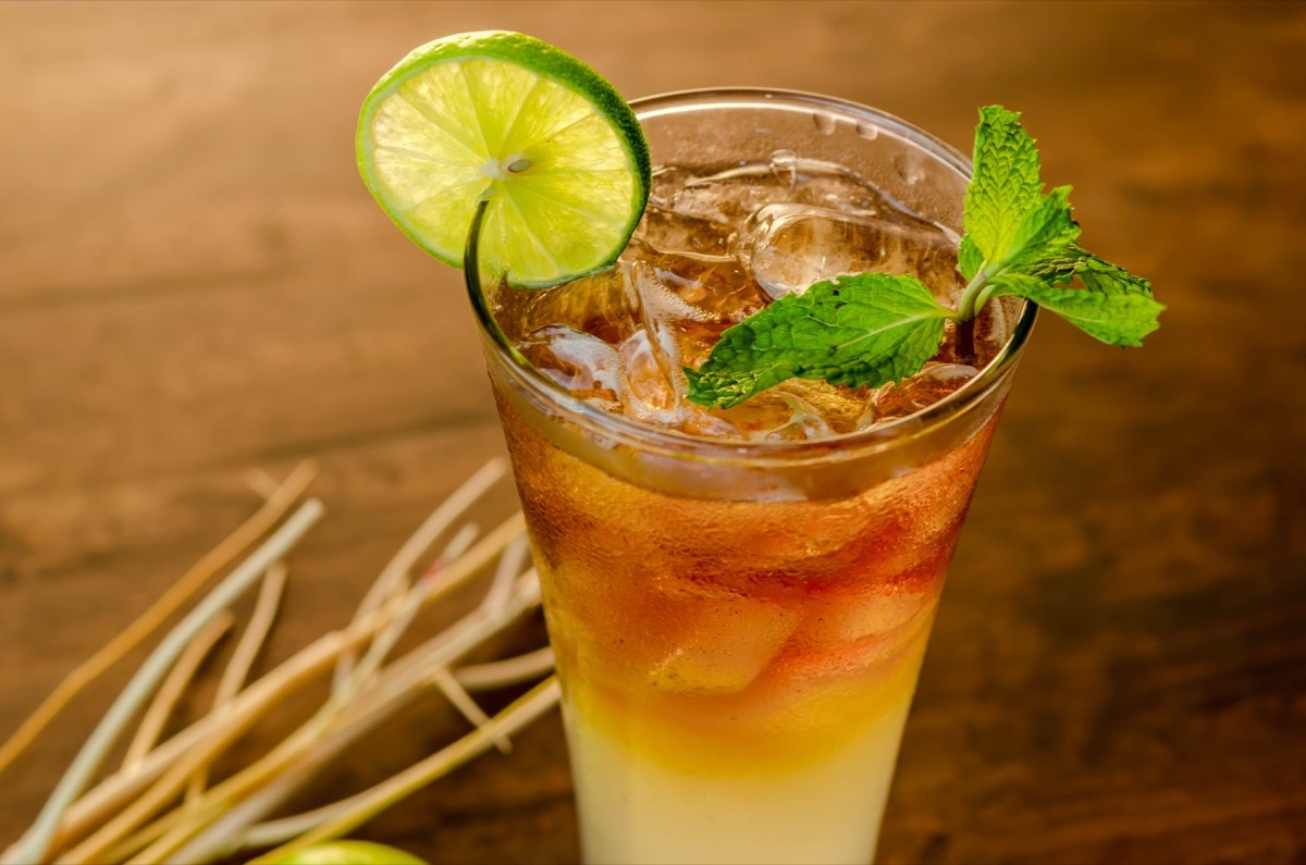 long island iced tea, cocktail in glass with lime on table