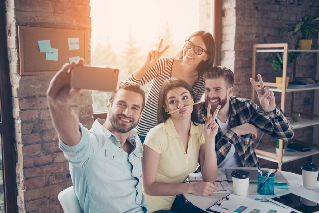 coworkers taking a selfie in a brick-walled office