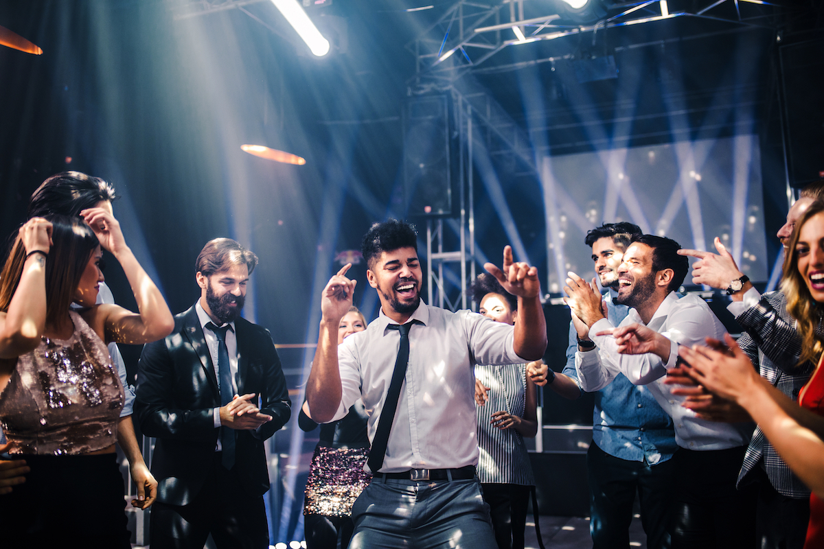 Shot of a young man in a shirt and tie dancing in the middle of a circle of people at the club