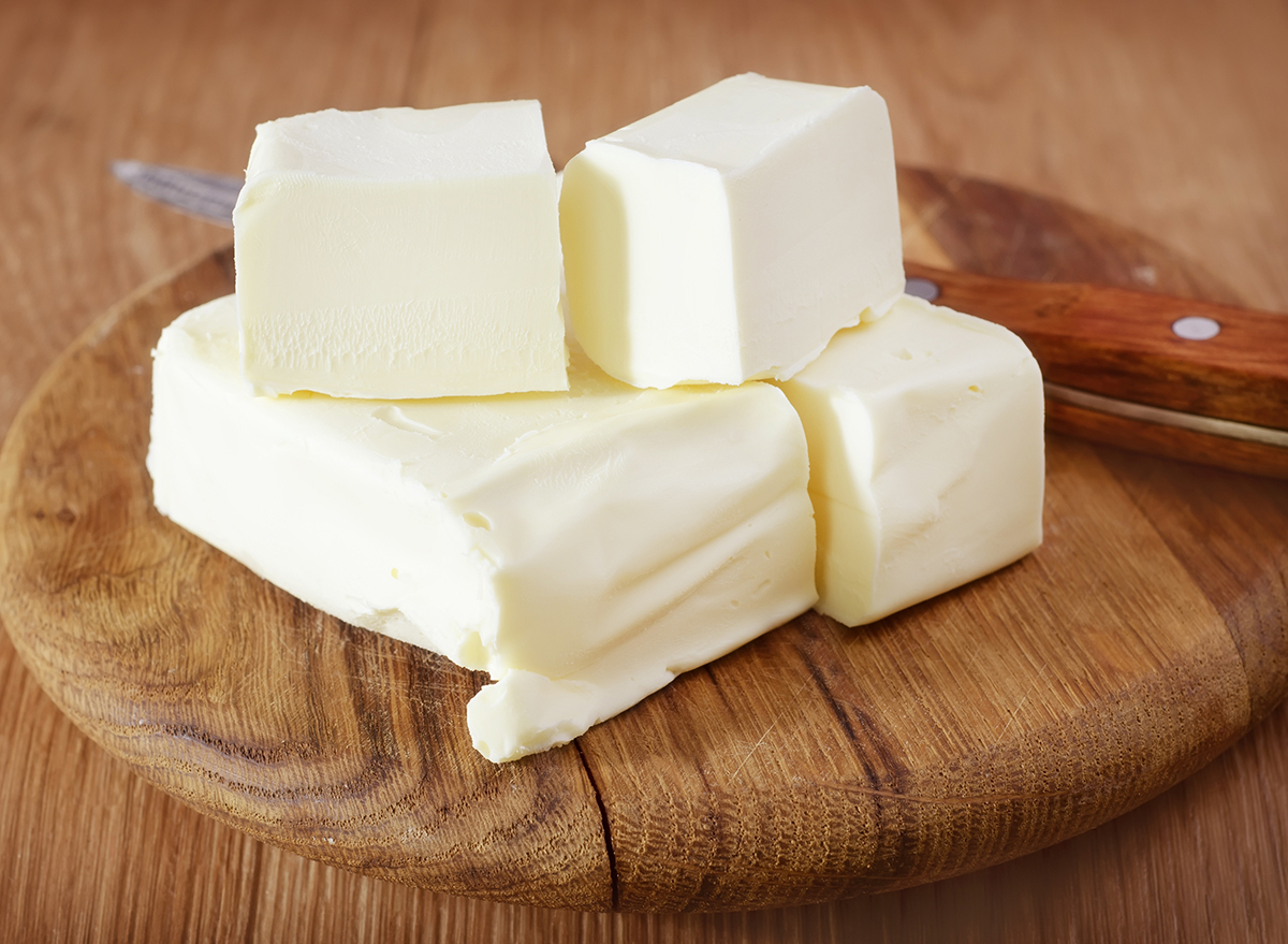 sticks of butter stacked on top of a wooden board next to a knife