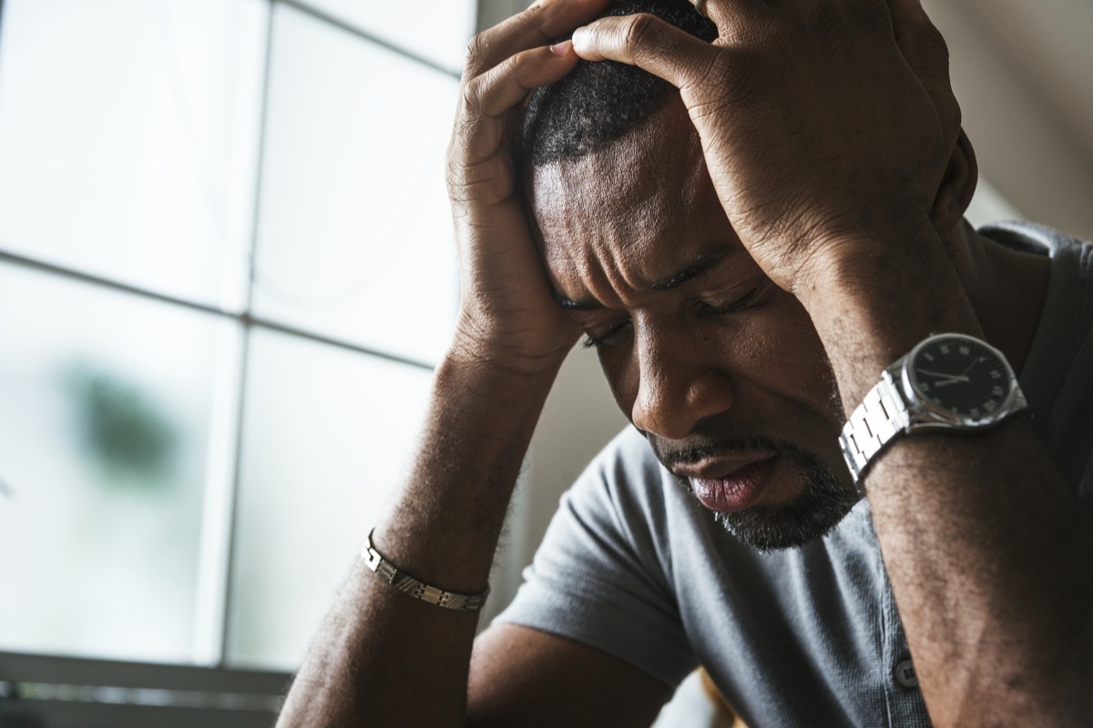 Black guy stressing with his head in his hands and a headache