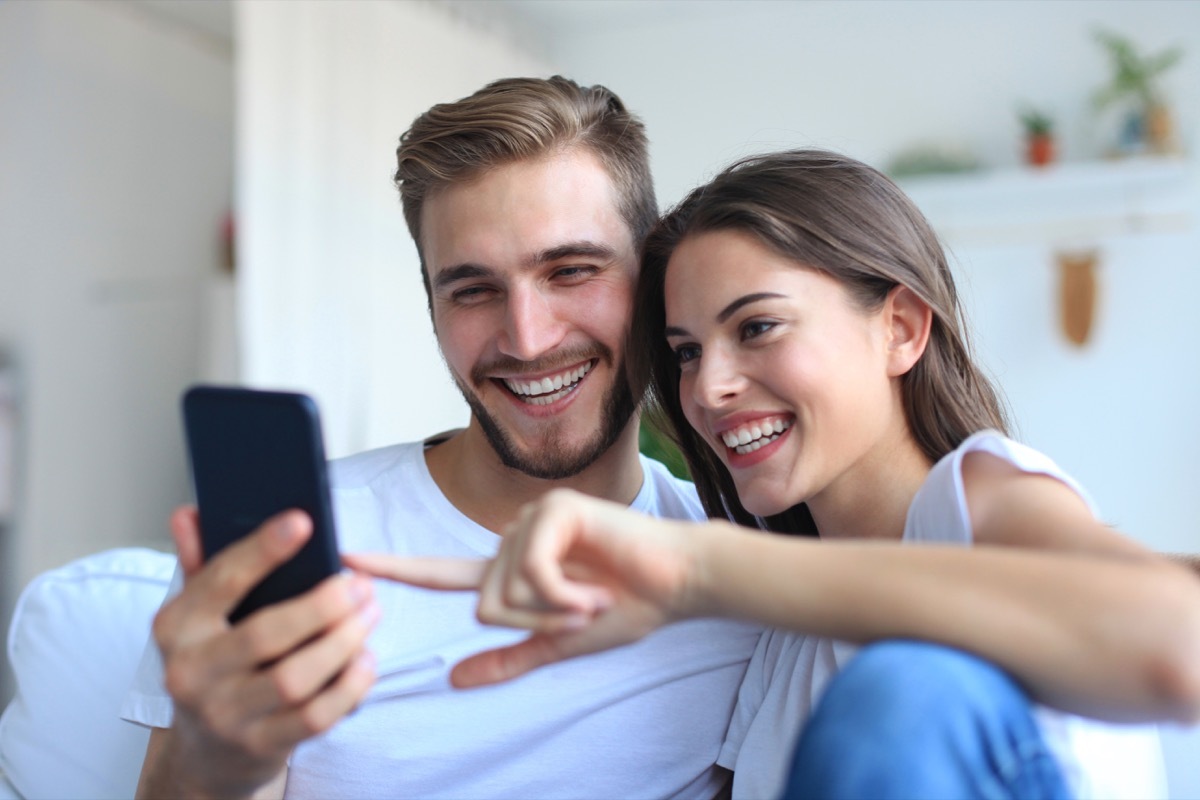 Couple looking and laughing at phone on couch