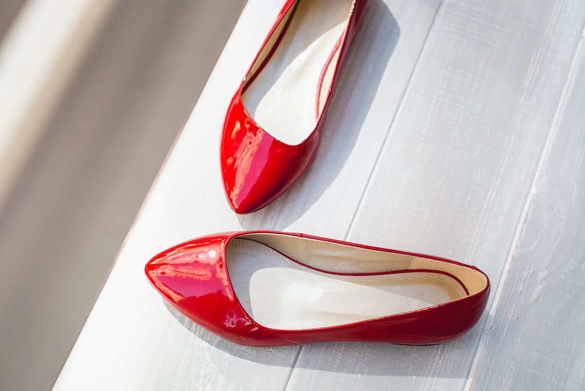 red leather flats shoes on a white wooden background