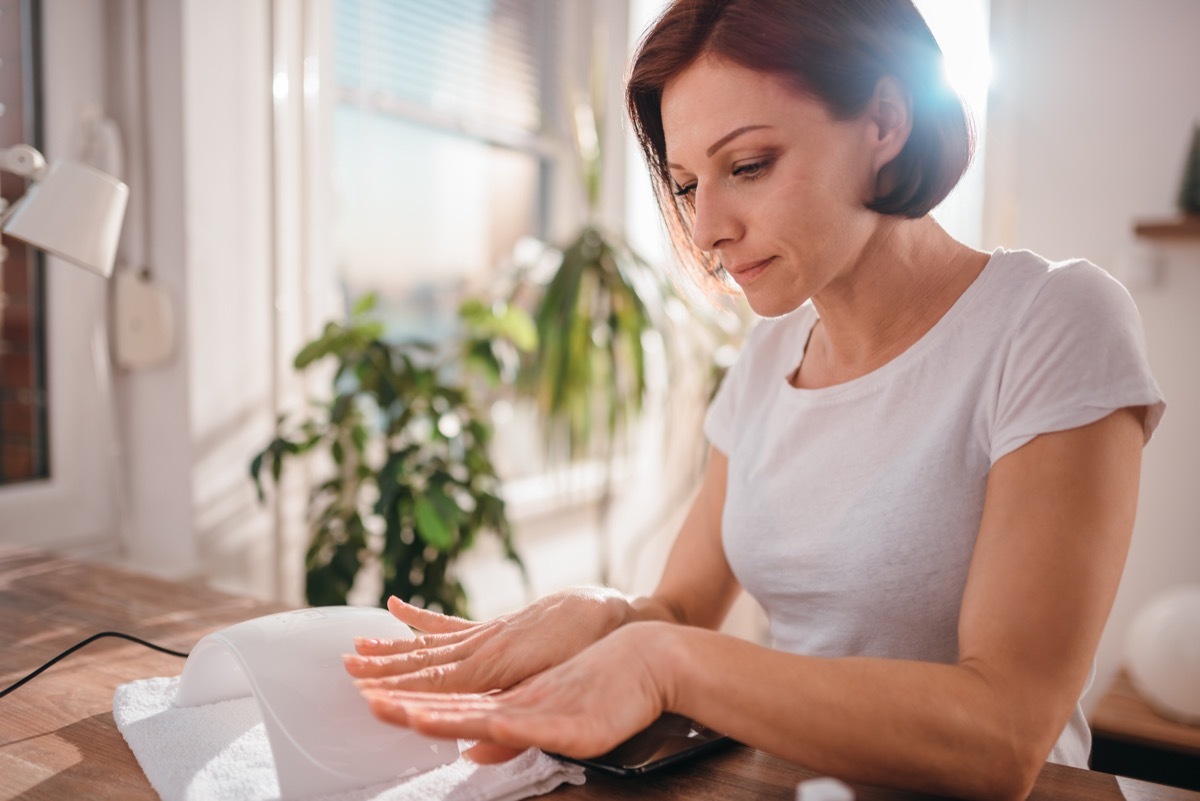 woman wearing white shirt, looking at nails