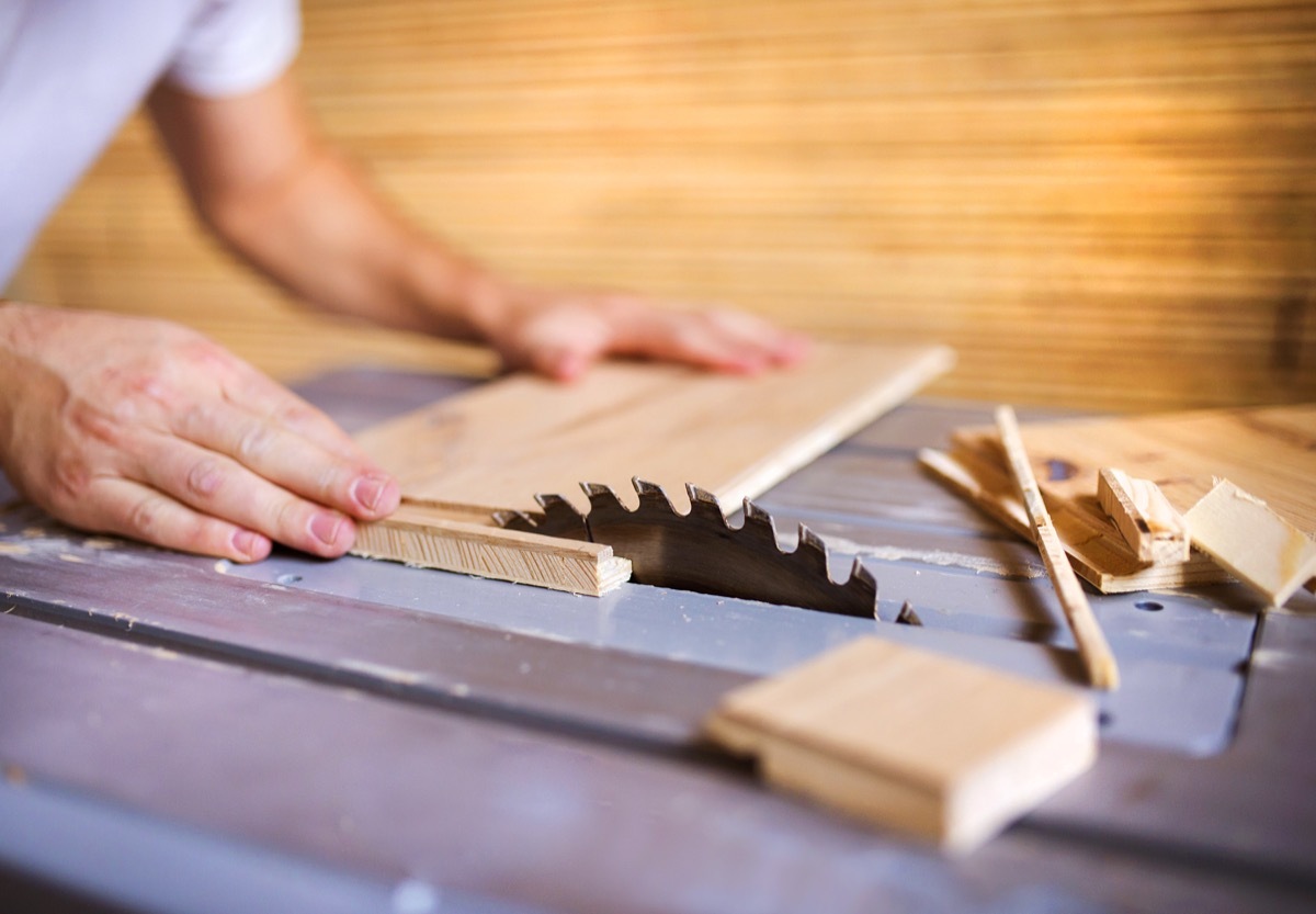 Unrecognizable handyman cutting plywood on circular saw in the new house