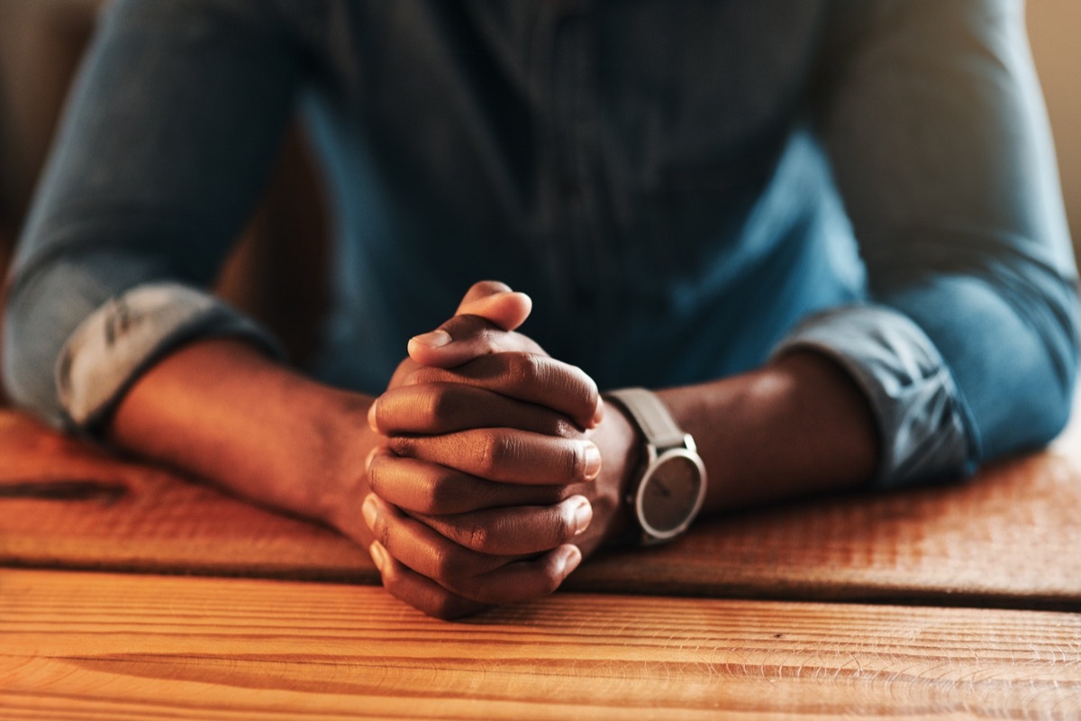 Cropped shot of an unrecognizable businessman sitting with his hands together in his home office and praying