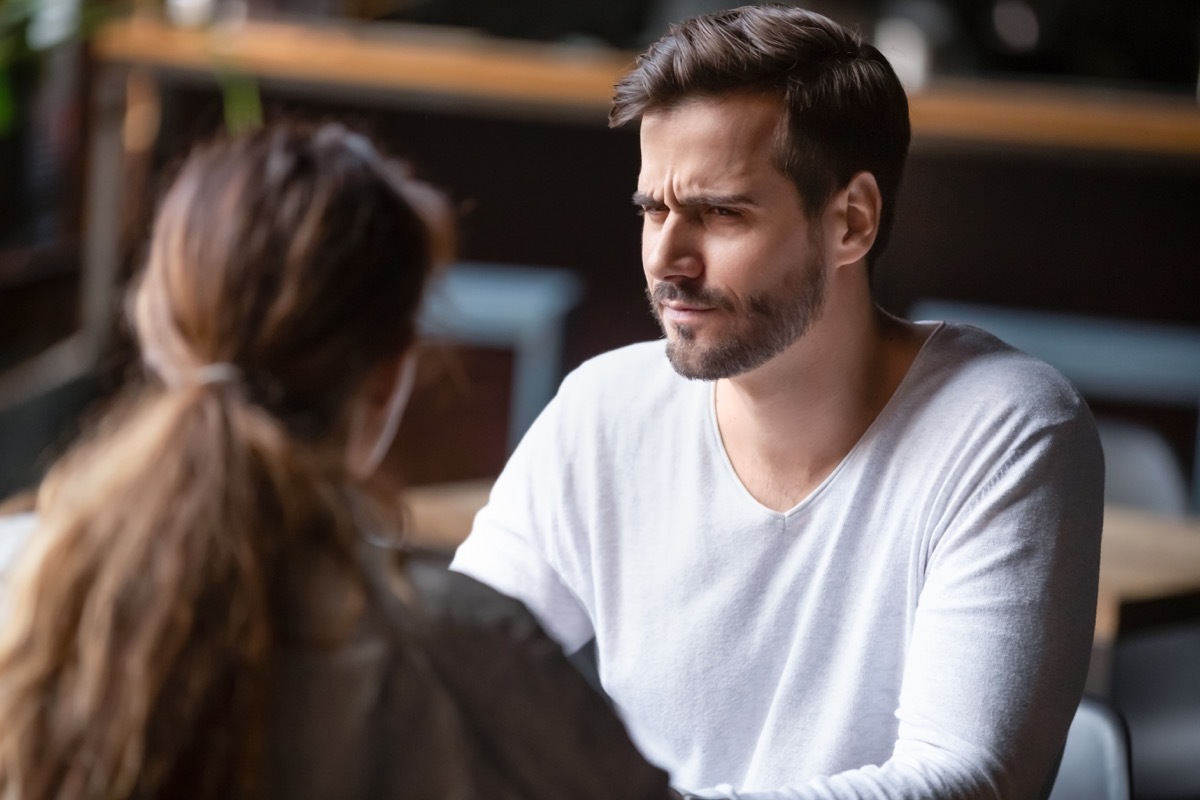 Doubting dissatisfied man looking at woman, bad first date concept, young couple sitting at table in cafe, talking, bad first impression, new acquaintance in public place, unpleasant conversation