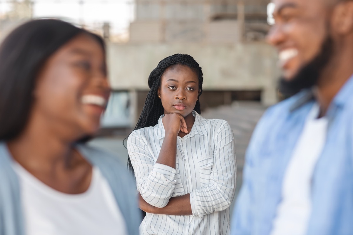 Woman upset looking at her partner flirting with another woman.