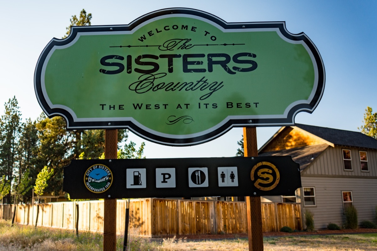 Welcome sign for the town of Sisters Oregon at dusk in the summer reads The West At Its Best, state fact about oregon