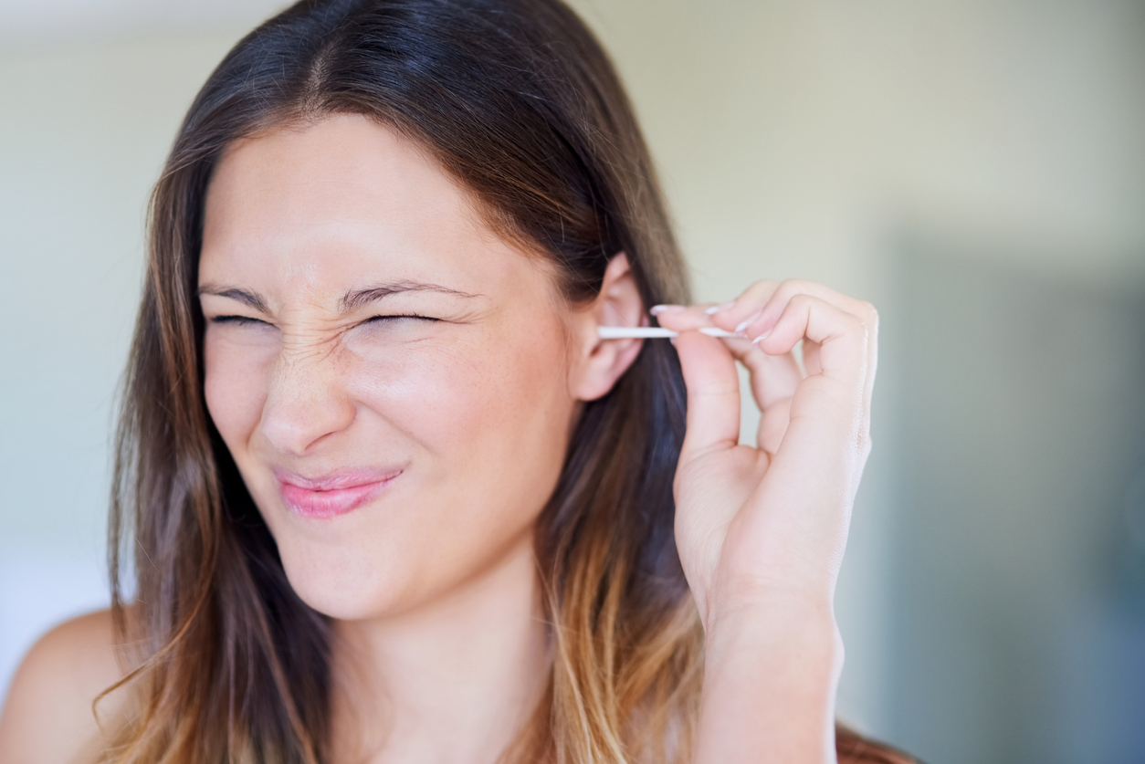 Woman cleaning her ear with a q-tip.