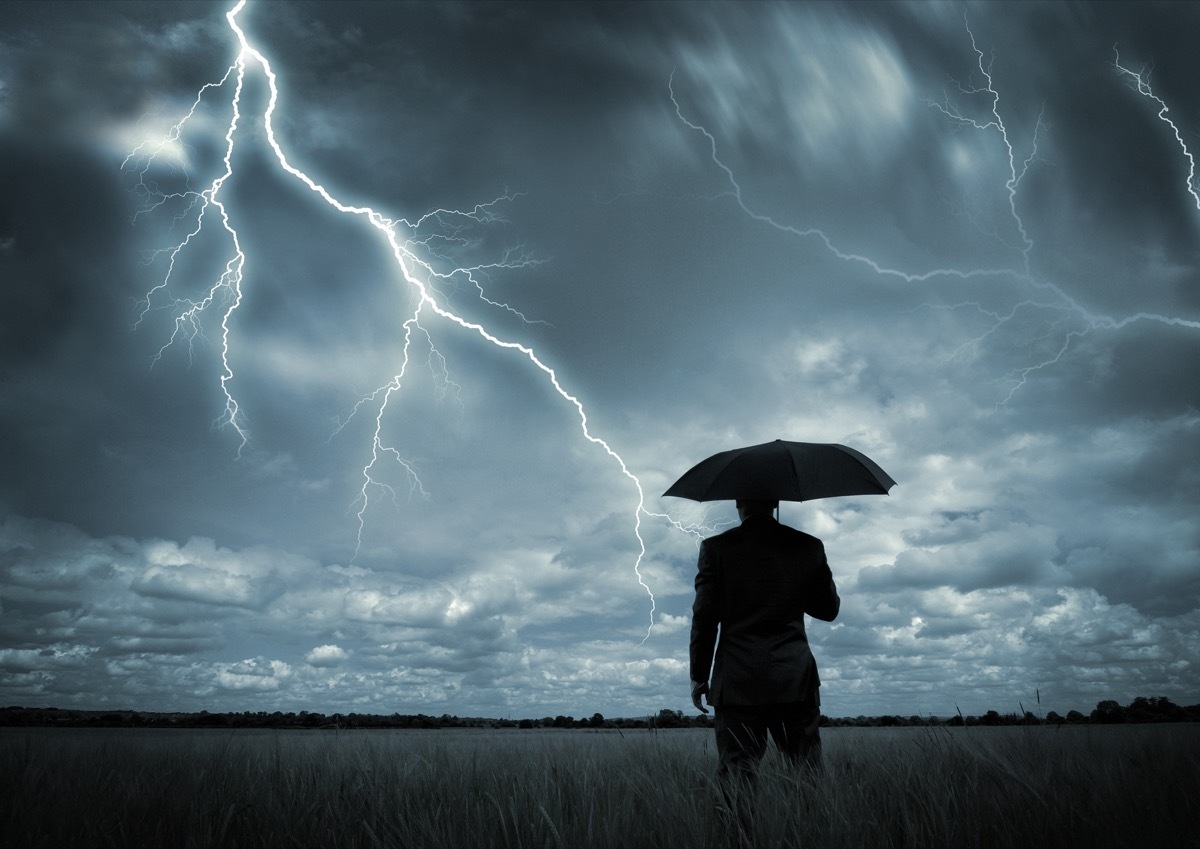 A businessman holding an umbrella in a storm