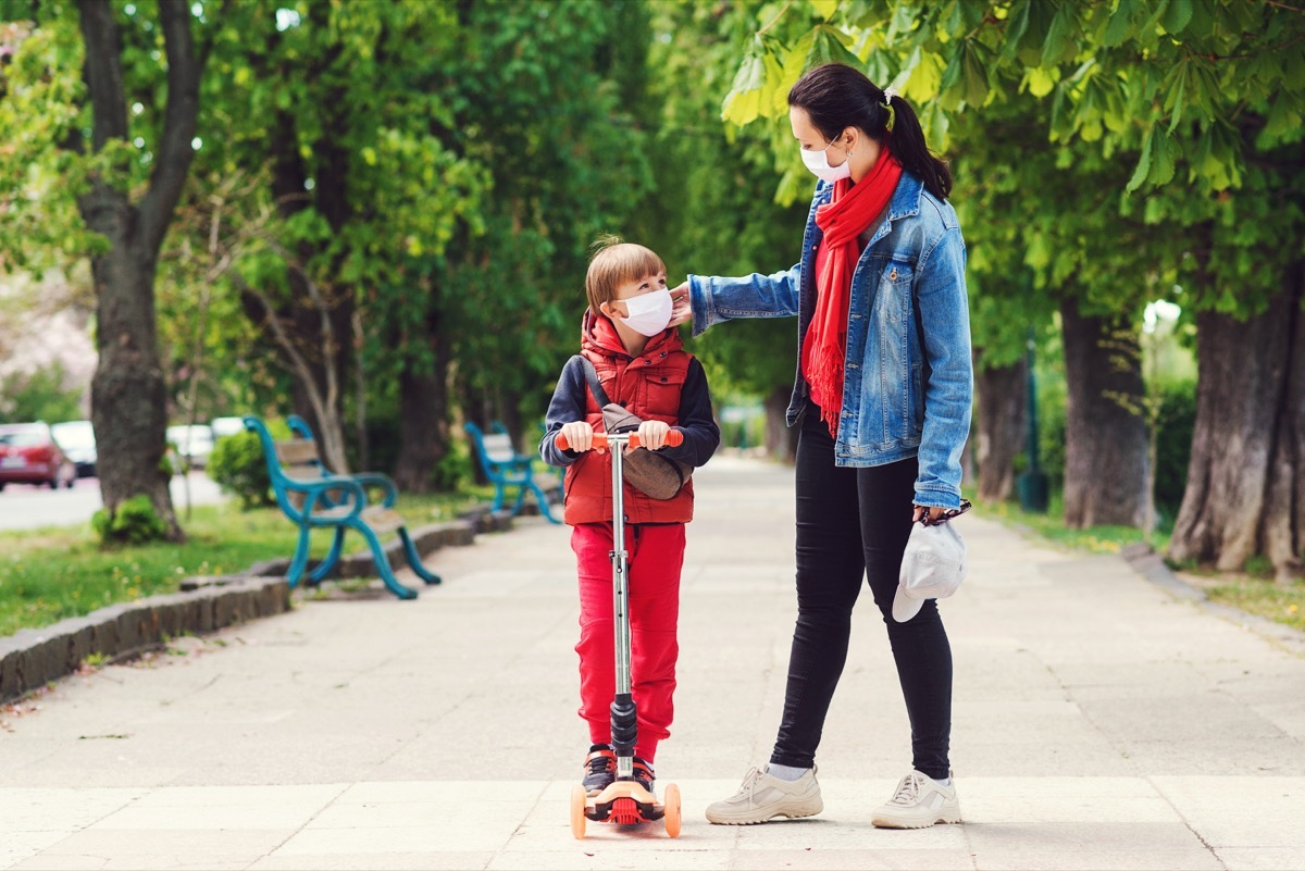 Mother and son walking and scootering with masks on