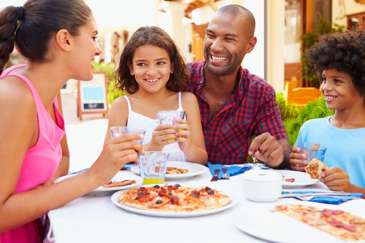 a family of four sits around an outdoor table at a restaurant