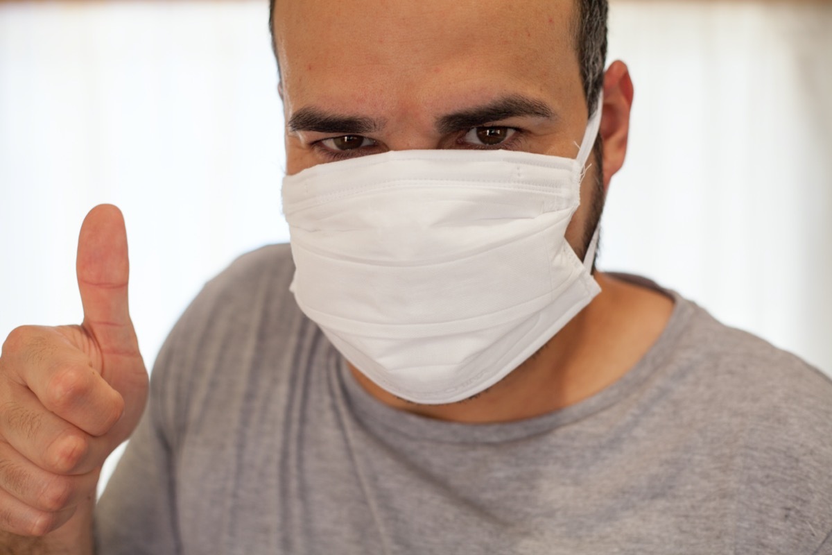 Man with a very optimistic and positive coronavirus mask with his thumb up.