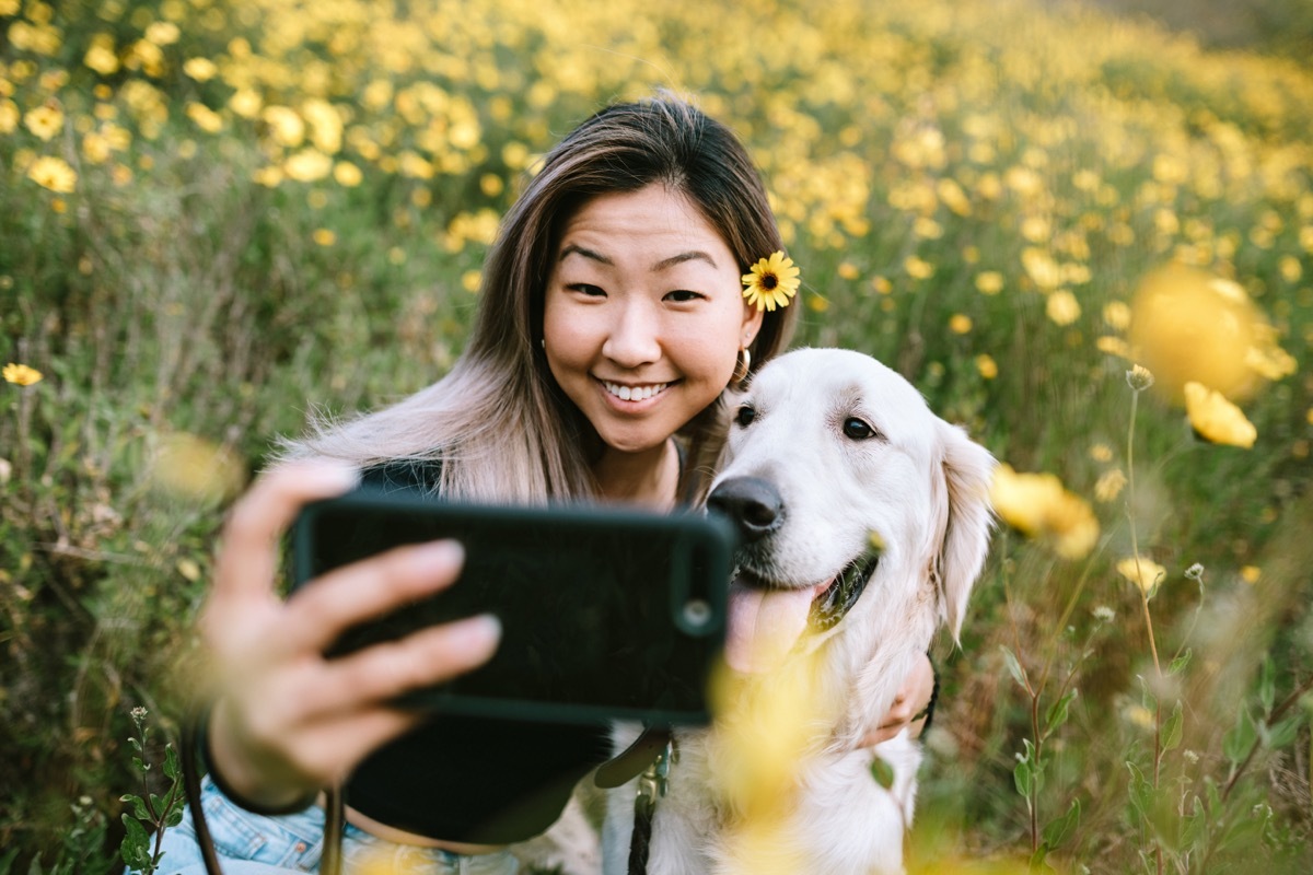 A happy woman enjoys spending time with her Golden Retriever outdoors in a Los Angeles county park in California on a sunny day. She cuddles her beloved pet.