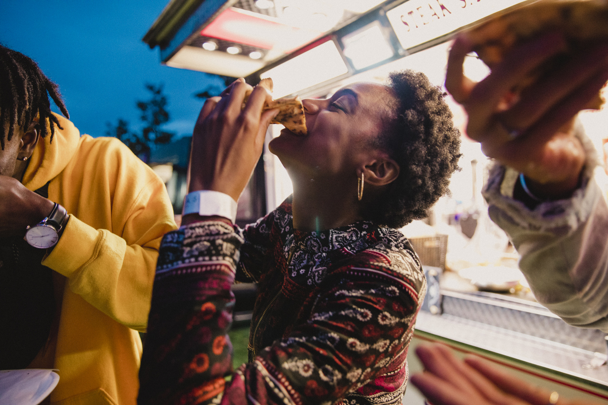 A young women enjoying pizza with friends at a music festival.