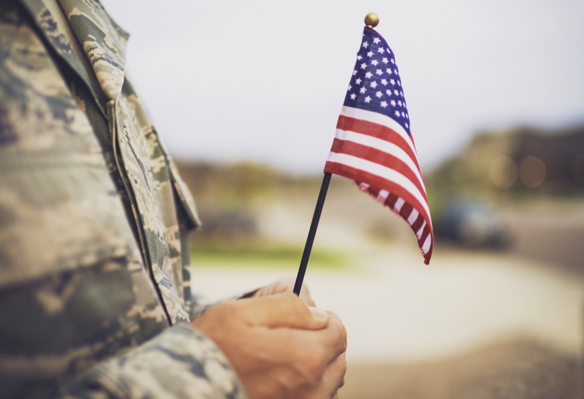 military man holding american flag - veterans day quotes