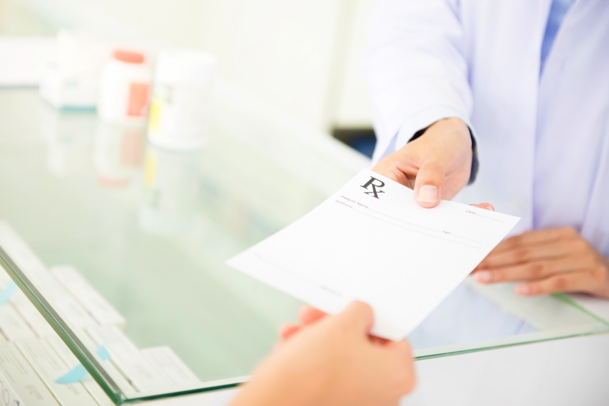 person handing prescription to pharmacist