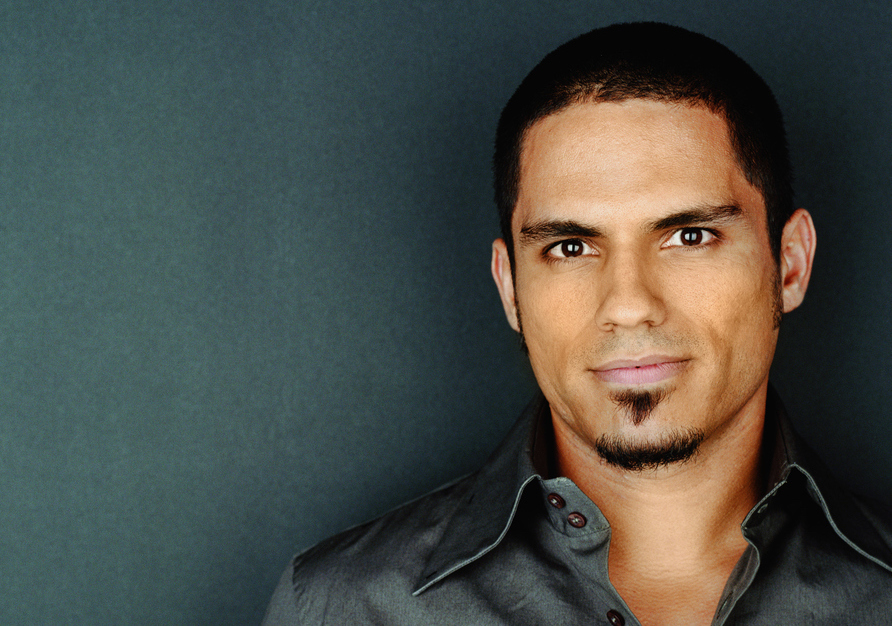 Portrait of a young man with a soul patch against a dark-green background