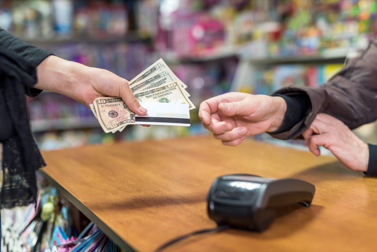 Female hand giving dollars and card to cashier as payment