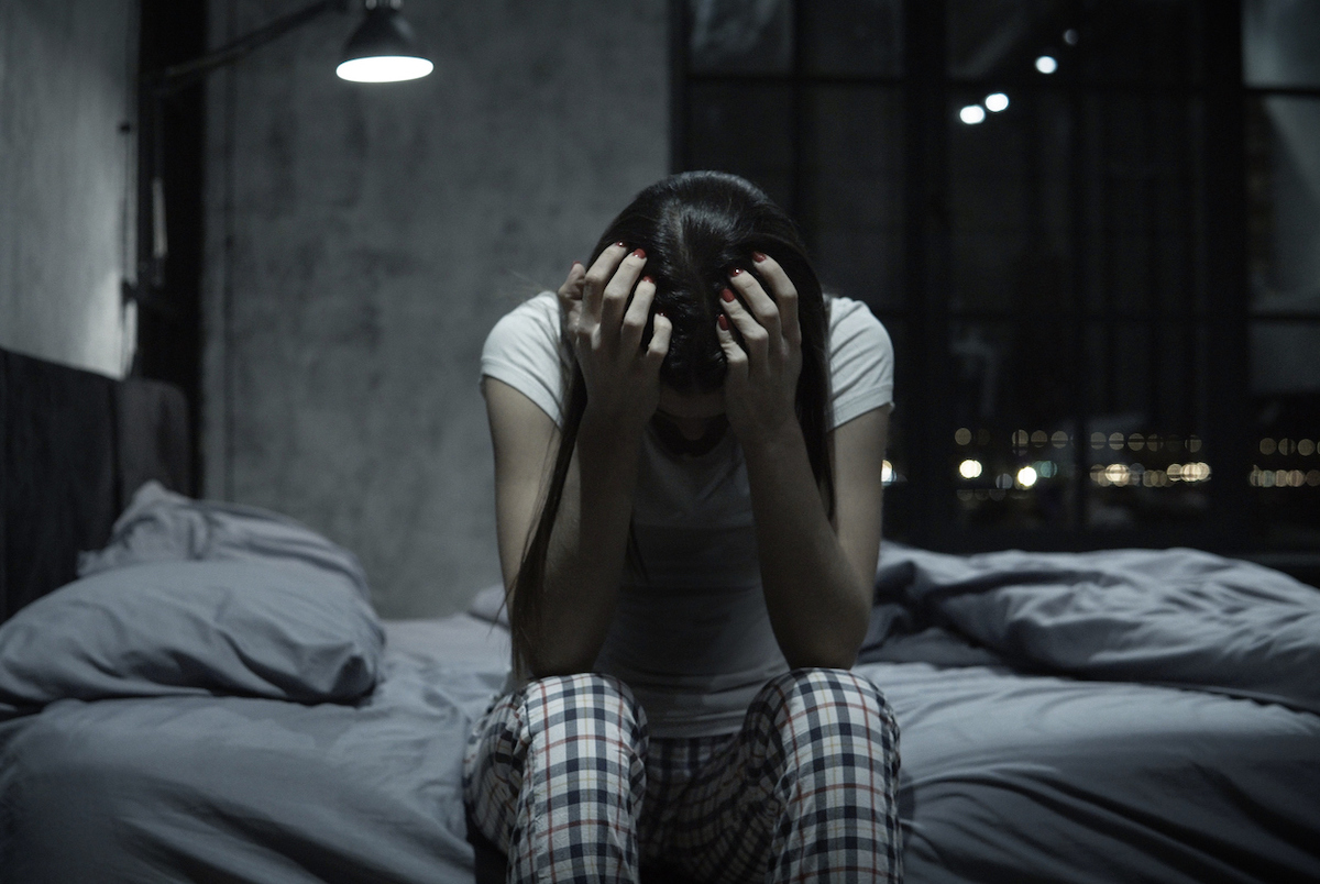 Young woman can't sleep, covering face with hands