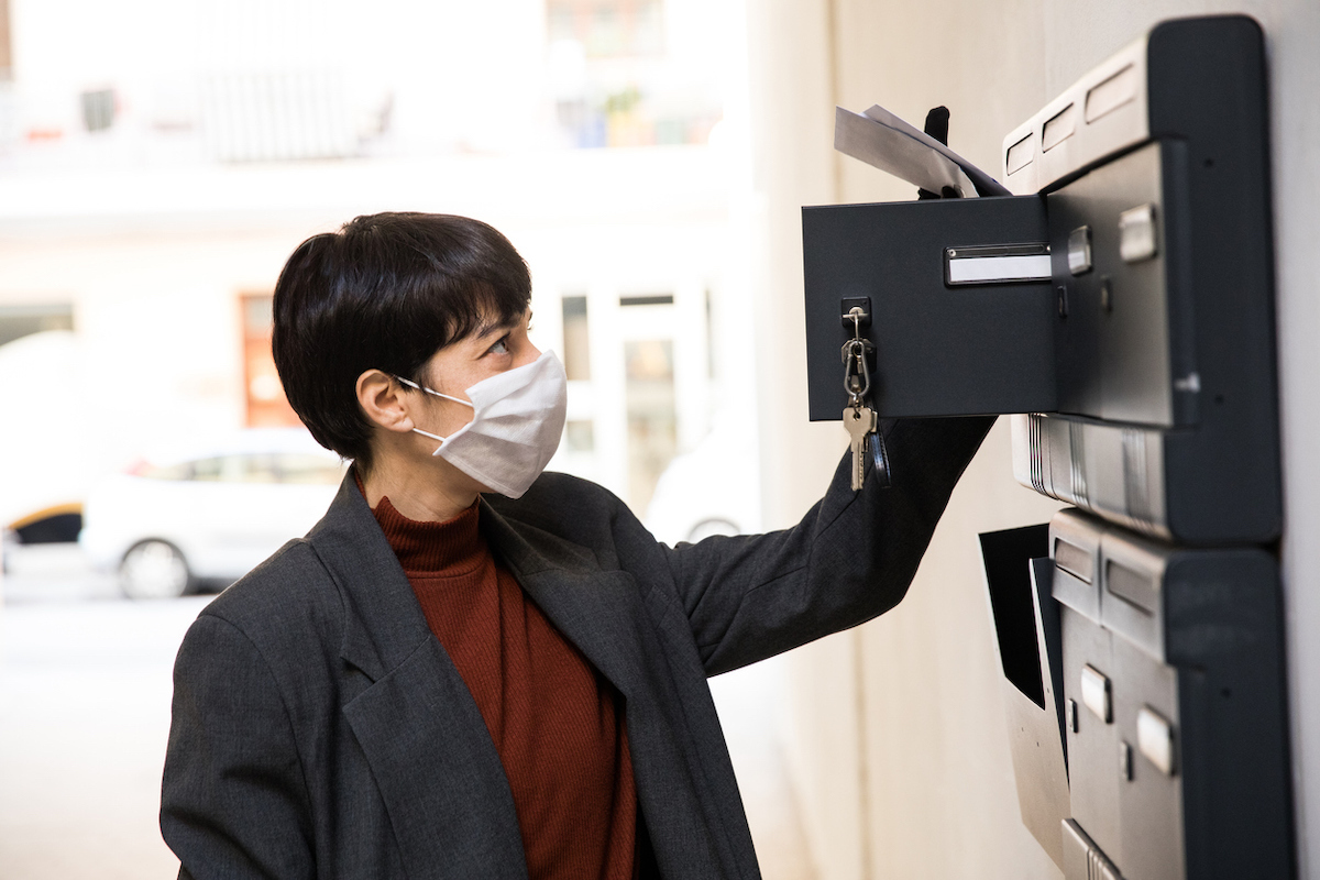 Woman arriving home after a day at work checking mailbox during Covid-19 pandemic.