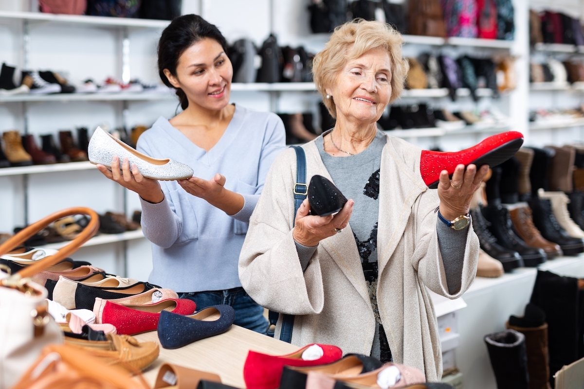 Friendly female sales consultant demonstrates ballet flats to a mature woman customer who came to a shoe store for shopping