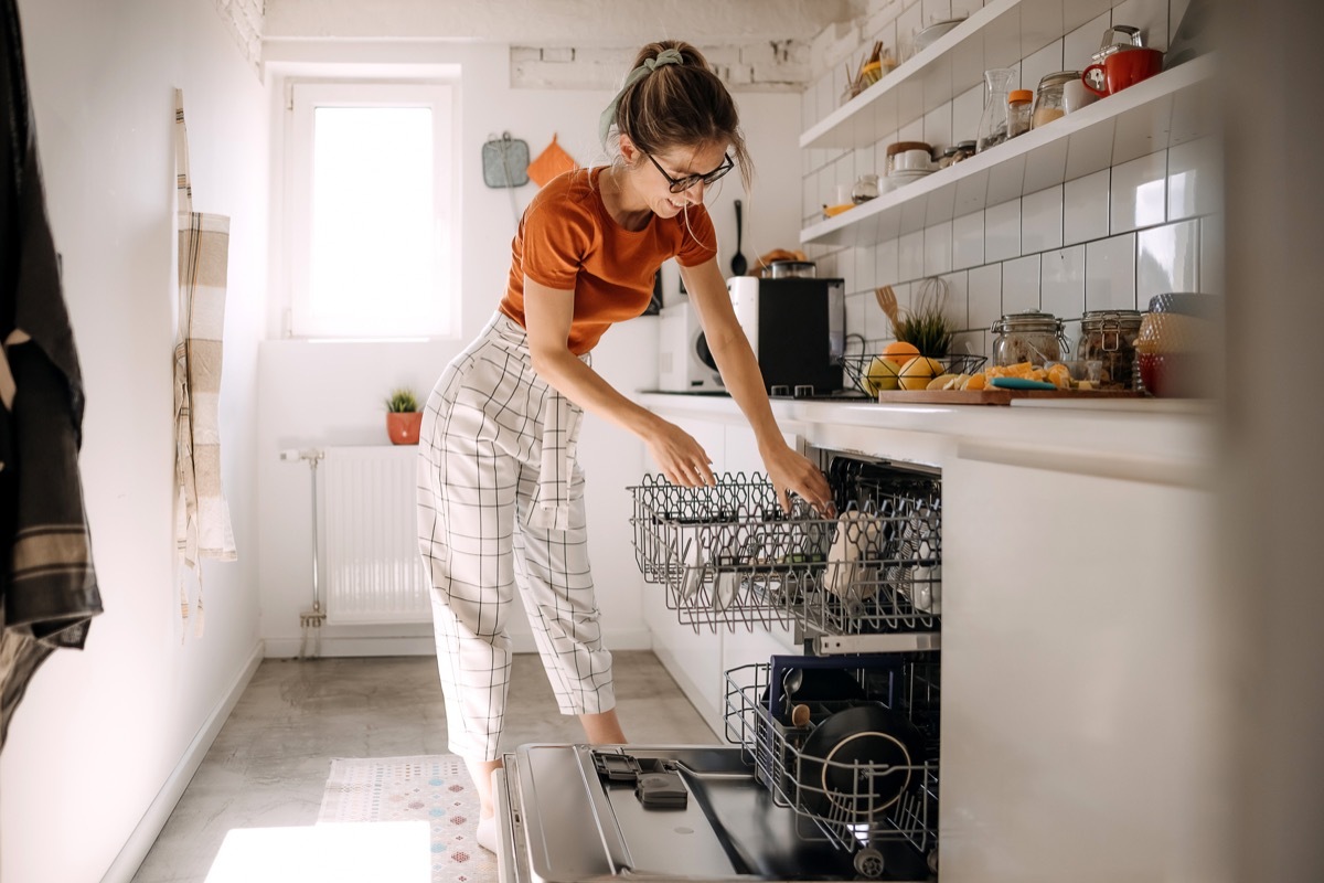 Young woman putting dishes in dishwashing machine