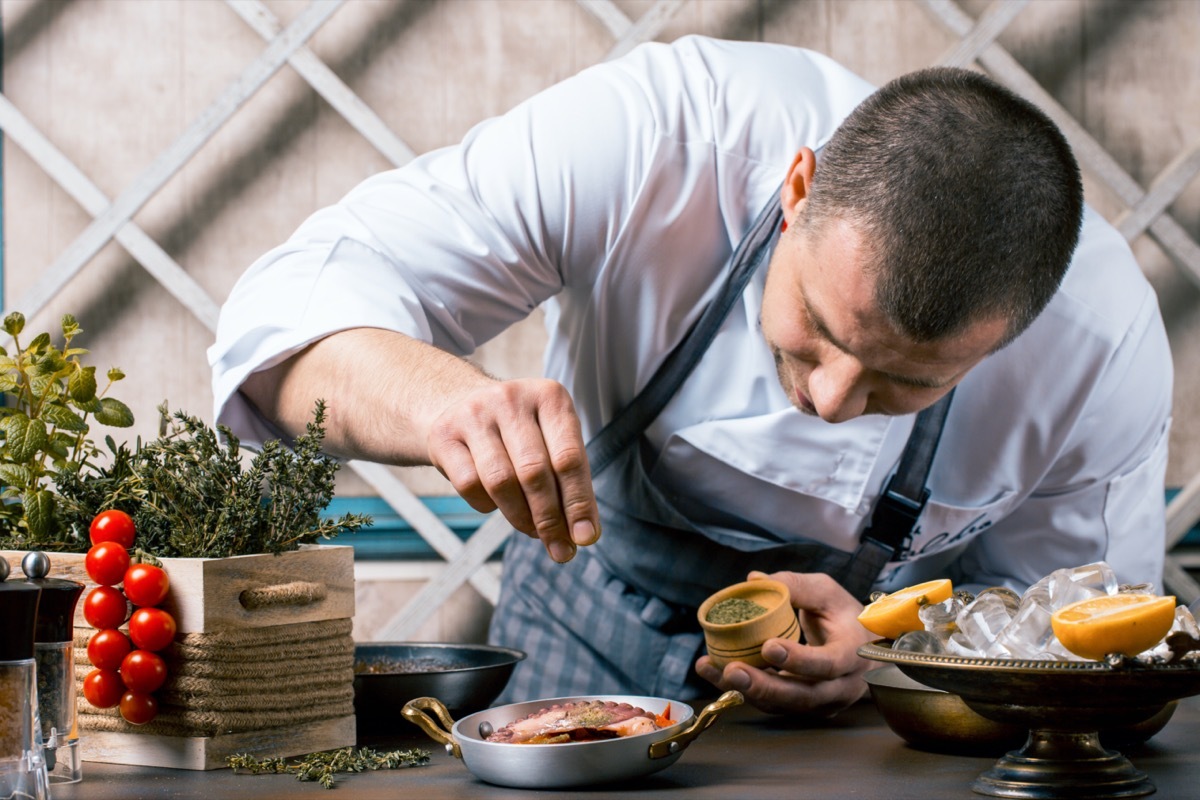 Royalty-free stock photo ID: 1041360706 Chef sprinkling spices on dish in kitchen