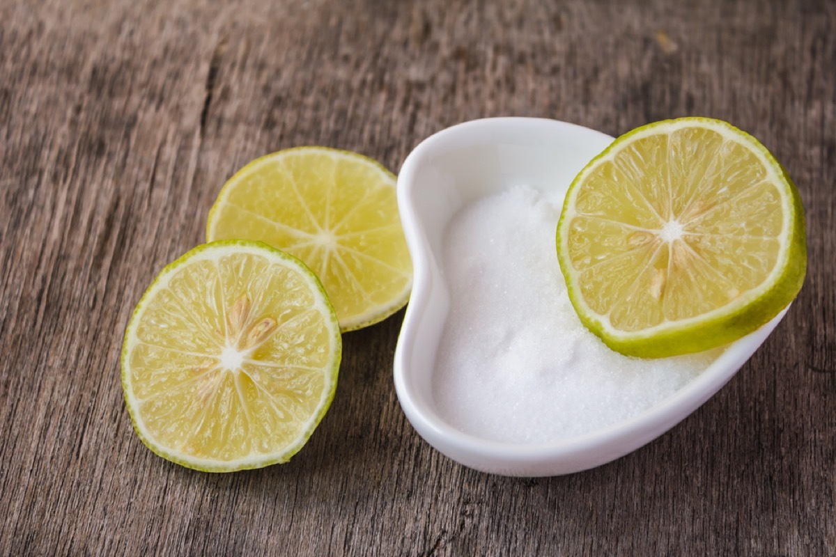 lime halves in and next to white ceramic bowl on wood counter