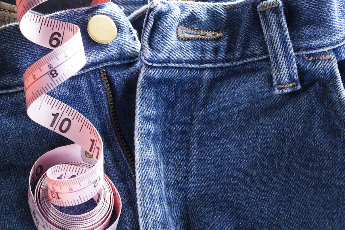 close up of blue jeans with measuring tape, concept for tailor or size of manhood.