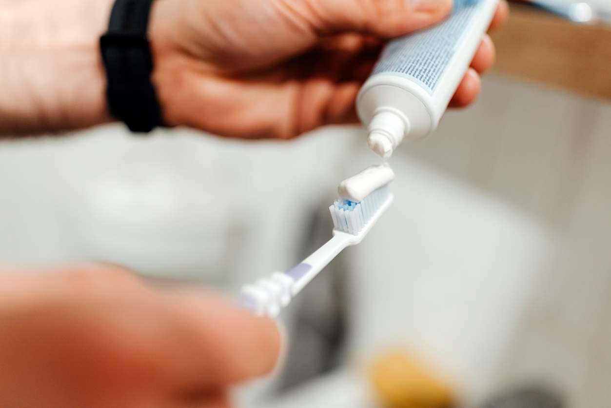 A closeup of hands squeezing toothpaste onto a toothbrush