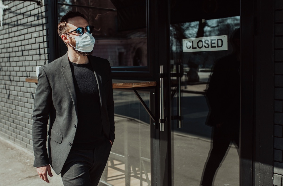 Handsome man with beard in trendy formal suit wearing a medical face mask