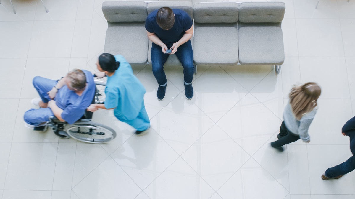 Hospital Lobby, Man Waits for Results while Sitting and Using Mobile Phone, Doctors, Nurses and Patients