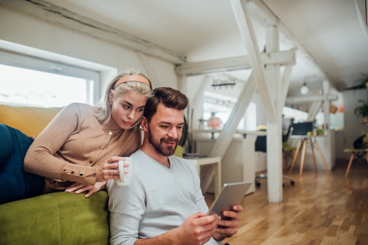 Happy young couple working from home, using digital tablet