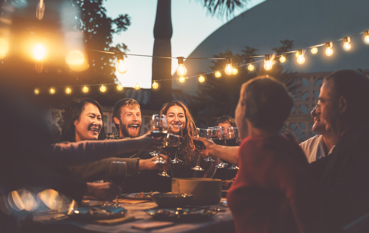 Happy family dining and tasting red wine glasses in barbecue dinner party - People with different ages and ethnicity having fun together - Youth and elderly parents and food weekend activities concept