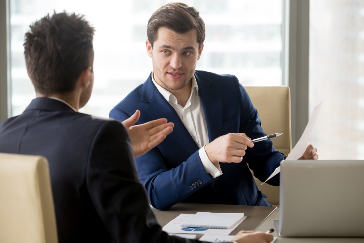 two men sitting across from each other at desk having a business meeting