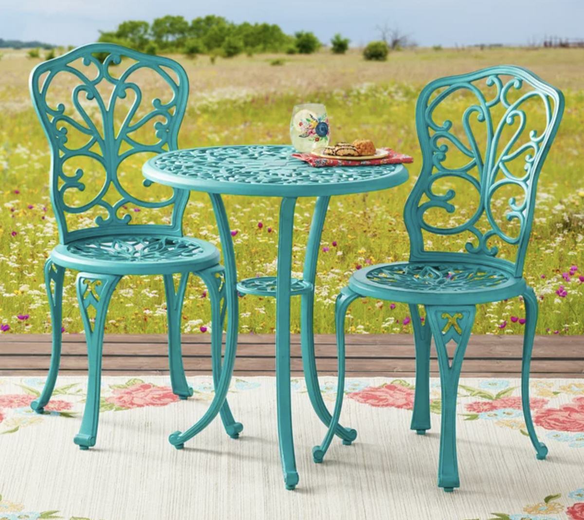 teal bistro set on an outdoor rug in a field