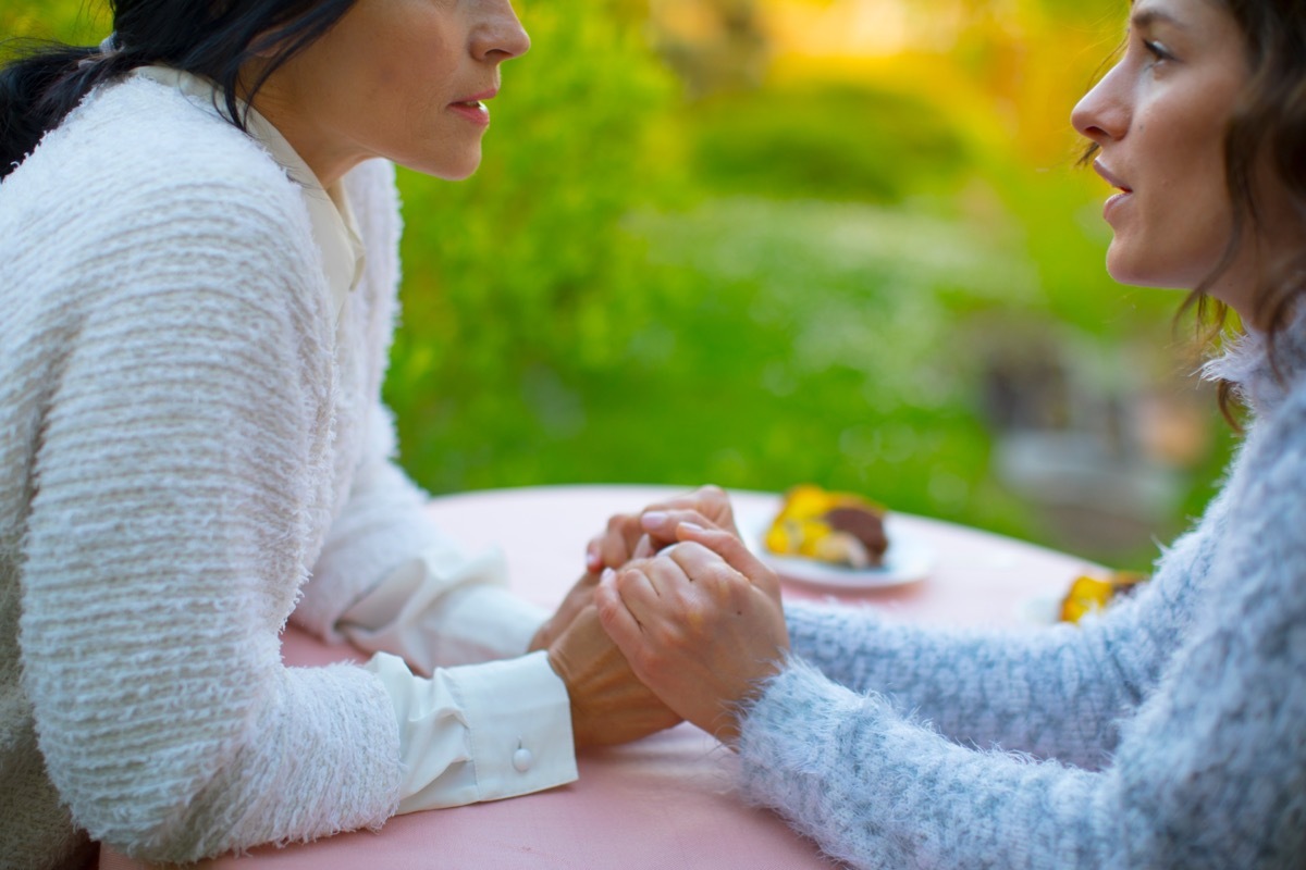 woman holding hands her with mother from across the table