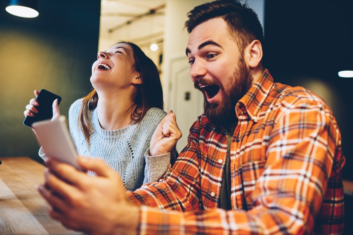 Excited-looking couple looking at a phone